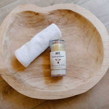 Bottle of BFF Yellow Deodorant on a wooden surface with a white towel
